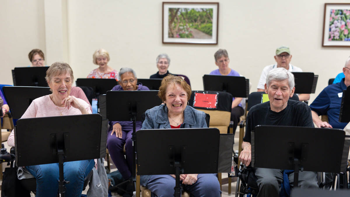 Members of the Parkinson Voice Project choir smile and sing in the rehearsal room