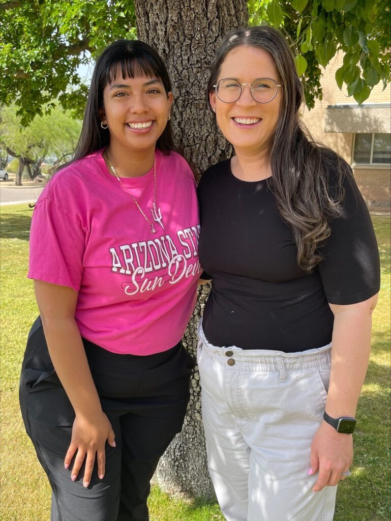 Elizabeth Trueba and Cindy Yahuaca standing side-by-side in front of a tree on a sunny day outside the Arizona State University Therapy & Research Center.